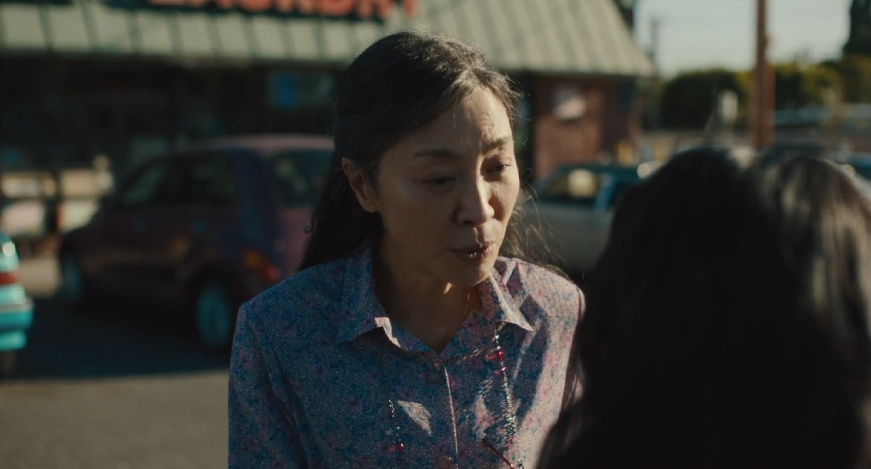 frame del film dove la protagonista e sul parcheggio della lavanderia parlando con la sua figlia che sta per salire alla macchina.