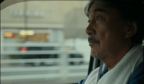 protagonista del film "perfect days" inquaddratura all'interno della macchina che guida.